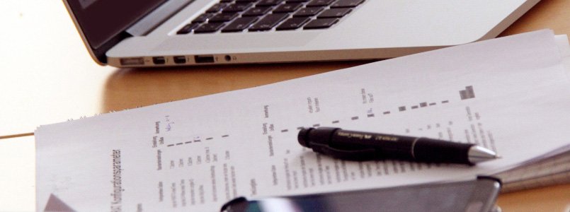 Workspace setup: A computer, calculator, and handwritten notes on a desk